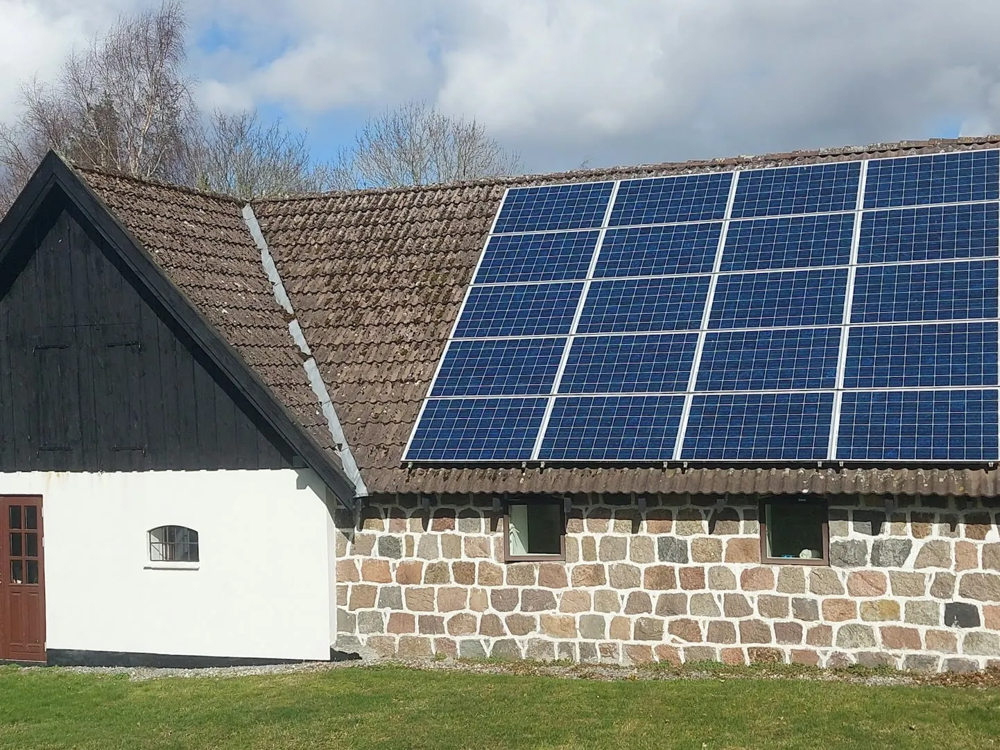 Solaranlage auf dem Dach einer Scheune am Ortsrand, Felder im Hintergrund