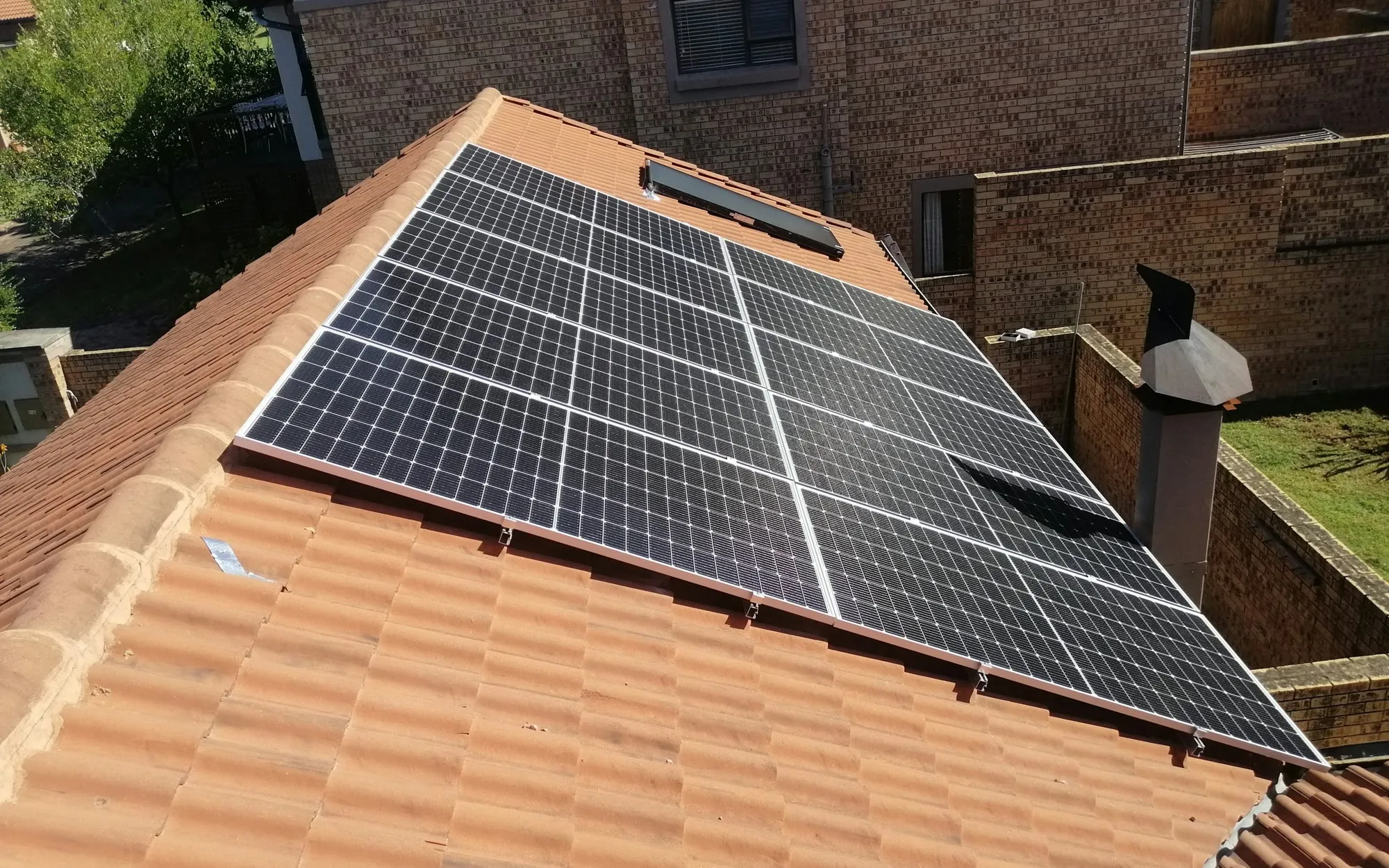 Reihen von Solarmodulen auf einem roten Ziegeldach im Abendlicht